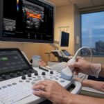 Ultrasound technician performing a scan in a modern medical clinic setting.